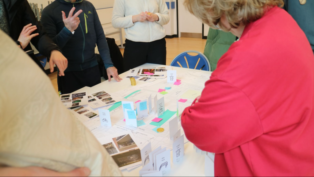 Photo showing day two of the consultation on the Golden Lane Estate with residents gathered round a table which has a map and cards on it.