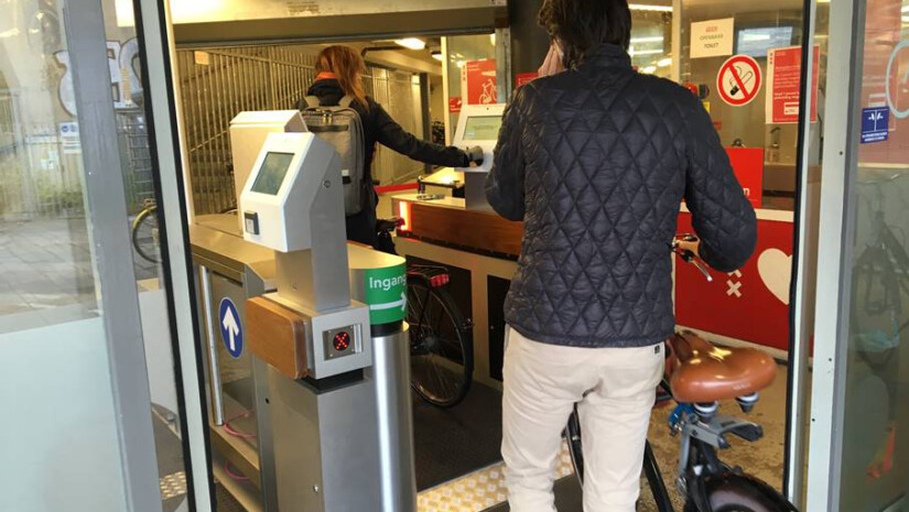 Man and woman with bikes going through gate of parking garage