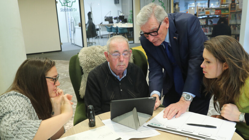 4 People looking at a digital screen.
