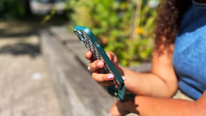 Person sitting outside looking at a smartphone.